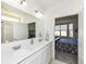 Bright main bathroom featuring double sinks, a large mirror, and white cabinets with view to adjacent bedroom at 936 Plunkett Ave, Westfield, IN 46074