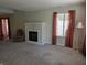 A cozy living room featuring a fireplace, carpet flooring, and natural light from a large window at 9808 Worthington Blvd, Fishers, IN 46038
