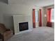 A cozy living room featuring a fireplace, carpet flooring, and natural light from a large window at 9808 Worthington Blvd, Fishers, IN 46038