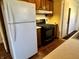 Kitchen with gas stove, white fridge and laminate floors plus access to a pantry and hallway at 1031 Schleicher Ave, Indianapolis, IN 46229