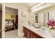 Bathroom with double sinks, cherry cabinets, and a doorway leading into the bedroom at 10535 Pokagon Way, Indianapolis, IN 46239