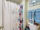 Floral shower curtain next to a toilet with folded towels in a neutrally painted bathroom at 10535 Pokagon Way, Indianapolis, IN 46239