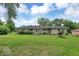 Spacious backyard of ranch-style home with green lawn and mature trees, perfect for outdoor activities at 120 E Beechwood Ln, Indianapolis, IN 46227