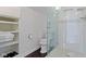 White bathroom with glass enclosed shower, toilet, and shelving unit at 1471 N Delaware St, Indianapolis, IN 46202