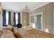 Inviting bedroom with a chandelier, large windows with blue curtains, and display cabinet at 1471 N Delaware St, Indianapolis, IN 46202