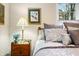 Close up of bedroom shows a nightstand with art, a lamp, flowers, and natural light from the large window at 1794 Bell Rd, Morgantown, IN 46160