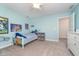 Bright bedroom features a twin bed, light blue walls, carpeted floors, and colorful artwork on the walls at 19477 Quilling Ln, Noblesville, IN 46062