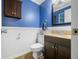Cozy half-bathroom with blue accent wall, decorative mirror, vanity with granite countertop, and tile flooring at 2305 Bill Smith Rd, Martinsville, IN 46151