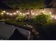 Nighttime backyard scene with string lights illuminating the garden and comfortable seating, creating a magical atmosphere at 2615 Kessler Blvd E Dr, Indianapolis, IN 46220