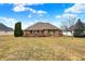 Spacious backyard view of the brick home with mature trees under a partly cloudy sky at 3801 S Cedar Creek Ln, New Palestine, IN 46163
