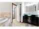 Bright bathroom features a soaking tub with stone surround and a modern vanity with a glass countertop at 6454 Bay Harbor Ln, Indianapolis, IN 46254
