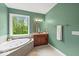 Bright bathroom with double vanity, soaking tub under window, and green painted walls at 681 Greenford N Trl, Carmel, IN 46032