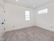Neutral bedroom featuring two windows, neutral carpet, white walls, and a closet with a black door knob at 711 N Fenton Ave, Indianapolis, IN 46219