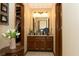 Well-lit bathroom with a wooden vanity, decorative flowers, and a large mirror at 7971 Clearwater Ct, Indianapolis, IN 46256