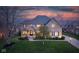 Charming two-story brick home with a manicured lawn and mature trees under a vibrant sunset sky at 10802 Giselle Way, Fishers, IN 46040