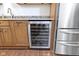 Kitchenette with wooden cabinets, granite countertop, wine fridge, stainless steel appliances, and tile flooring at 12396 Dellfield W Blvd, Carmel, IN 46033