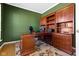 Spacious office with custom wood built-ins, large desk, and green walls, perfect for a home office at 12396 Dellfield W Blvd, Carmel, IN 46033