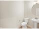 Contemporary half bathroom featuring a pedestal sink, round mirror, and elongated toilet on wood-look flooring at 14383 Coyote Ridge Dr, Noblesville, IN 46060