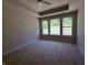 Bright bedroom with neutral carpet, a ceiling fan, tray ceiling and three large windows offering backyard views at 14383 Coyote Ridge Dr, Noblesville, IN 46060
