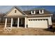 Charming single-story home featuring a two-car garage, covered porch, and light beige siding, nestled on a treed lot at 14383 Coyote Ridge Dr, Noblesville, IN 46060