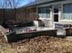 A patio with outdoor seating, a lattice fence, and a cooler on a concrete surface in a yard covered in leaves at 1459 S Josephine St, Martinsville, IN 46151