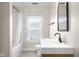 Modern bathroom featuring a floating vanity, bathtub, window with blinds, and neutral paint at 1714 Elm St, Columbus, IN 47201
