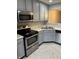 Close-up of a kitchen featuring stainless steel oven and microwave with gray cabinets, ample counter space, and neutral flooring at 504 Elkhart Dr, Westfield, IN 46074