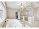 Bright bathroom featuring a soaking tub and glass enclosed shower near a bedroom entry at 6778 Old Hunt Club Rd, Zionsville, IN 46077