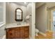Half bathroom with stylish vanity, carved wood mirror, fixtures and hardwood flooring at 6778 Old Hunt Club Rd, Zionsville, IN 46077