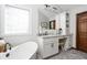 Bright bathroom featuring soaking tub, white vanity with granite counters and dark hardware at 7619 Bluebird Ct, Brownsburg, IN 46112