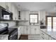 Modern kitchen featuring white cabinets, sleek black appliances, granite countertops, and tile backsplash at 7619 Bluebird Ct, Brownsburg, IN 46112