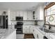 This kitchen features white cabinets with black hardware, granite countertops, stainless appliances, and stylish backsplash at 7619 Bluebird Ct, Brownsburg, IN 46112