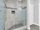 Bathroom shower with gray tile surround, glass door, shower niche, and built-in bench at 9657 Rialto Trl, Carmel, IN 46280