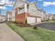 Exterior view of tan apartment building with a brick facade, green grass, and a blue sky at 9657 Rialto Trl, Carmel, IN 46280