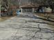 Long concrete driveway leading to a single-story home with a two-car garage in a wooded setting at 10128 E Troy Ave, Indianapolis, IN 46239