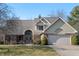 Charming two-story home featuring a brick facade, arched entryway, and attached two-car garage at 1110 Butternut Dr, Columbus, IN 47201