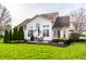 Spacious backyard with a patio, outdoor dining set, manicured shrubbery, and expansive green lawn at 11686 Belle Plaine Blvd, Fishers, IN 46037