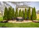Backyard sitting area on a stone patio with string lights, mature trees, and privacy landscaping at 11686 Belle Plaine Blvd, Fishers, IN 46037
