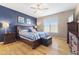Stylish bedroom featuring hardwood floors, blue accent wall, ceiling fan and natural light at 12610 Broadmoor N Ct, Fishers, IN 46037