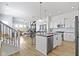 Open concept kitchen with stainless steel appliances, white cabinets, hardwood floors, and connected to the dining and living area at 13071 Pennington Rd, Fishers, IN 46037