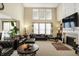 Bright living room with a fireplace, tall windows, and comfortable leather furniture at 14347 Camelot House Way, Fishers, IN 46037