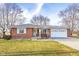 Charming single-story brick home featuring an attached two-car garage and well-maintained front lawn at 15620 E State Road 46, Columbus, IN 47203