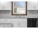 Close-up of the kitchen sink area, showcasing granite countertops, white cabinets, and subway tile backsplash at 15620 E State Road 46, Columbus, IN 47203