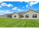 Lush backyard featuring multiple windows and a view of the grassy lawn under a vibrant, cloud-dotted sky at 1609 Clover Crossing Dr, Greenfield, IN 46140