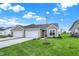 Charming single-story home with attached two-car garage and well-manicured lawn under a blue sky at 1609 Clover Crossing Dr, Greenfield, IN 46140