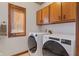 Functional laundry room featuring modern washer and dryer, wood cabinets and window for natural light at 2163 Laurel Leaf Ln, Avon, IN 46123