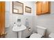 Cozy bathroom with tiled walls, a pedestal sink, wall cabinet and palm tree mirror at 229 W Taylor St, Pendleton, IN 46064