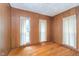 Bedroom with wood-paneled walls, hardwood floors, and three windows at 300 S Market St, Thorntown, IN 46071