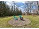 Backyard with stone fire pit and chairs next to a lush green lawn at 405 W 73Rd St, Indianapolis, IN 46260