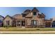 Charming exterior elevation with a stone and brick facade, covered porch, and well-manicured lawn at 4287 Prairie Falcon Dr, Zionsville, IN 46077